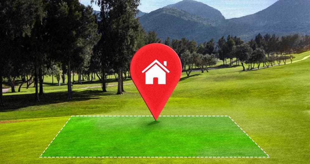 Marked-out rectangular building site on a cleared grass lot with a location pin
